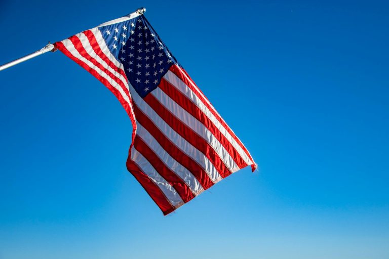 Die amerikanische Flagge flattert im Wind vor einem blauen Himmel.
