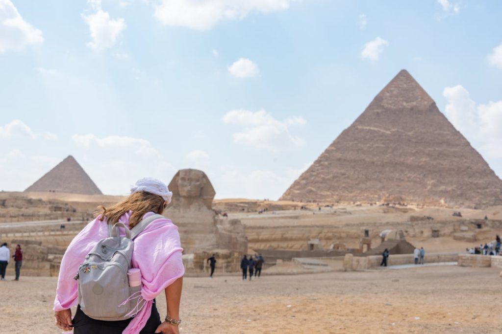 Eine Frau von hinten gesehen, die einen Rucksack trägt, während sie zu den Pyramiden in Ägypten läuft.