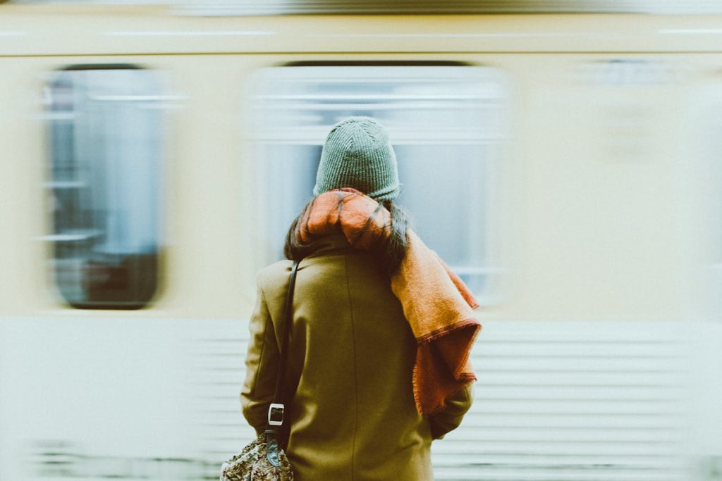 Eine von hinten gesehene Person mit einer Mütze vor einem abfahrenden U-Bahn-Waggon.