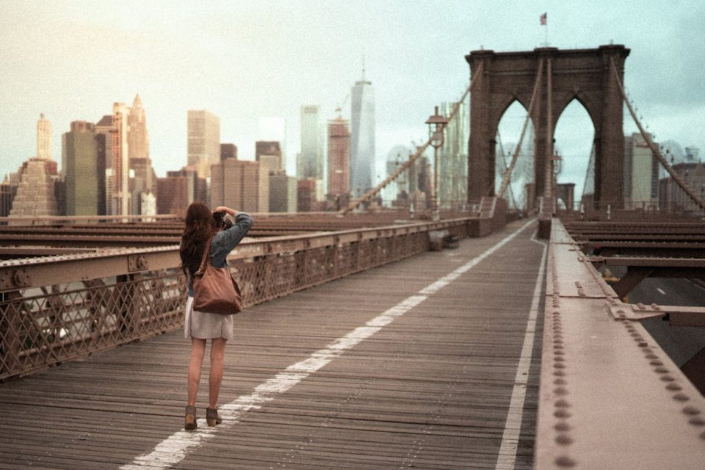 Eine junge Frau, die ein Foto von der Brooklyn Bridge macht.