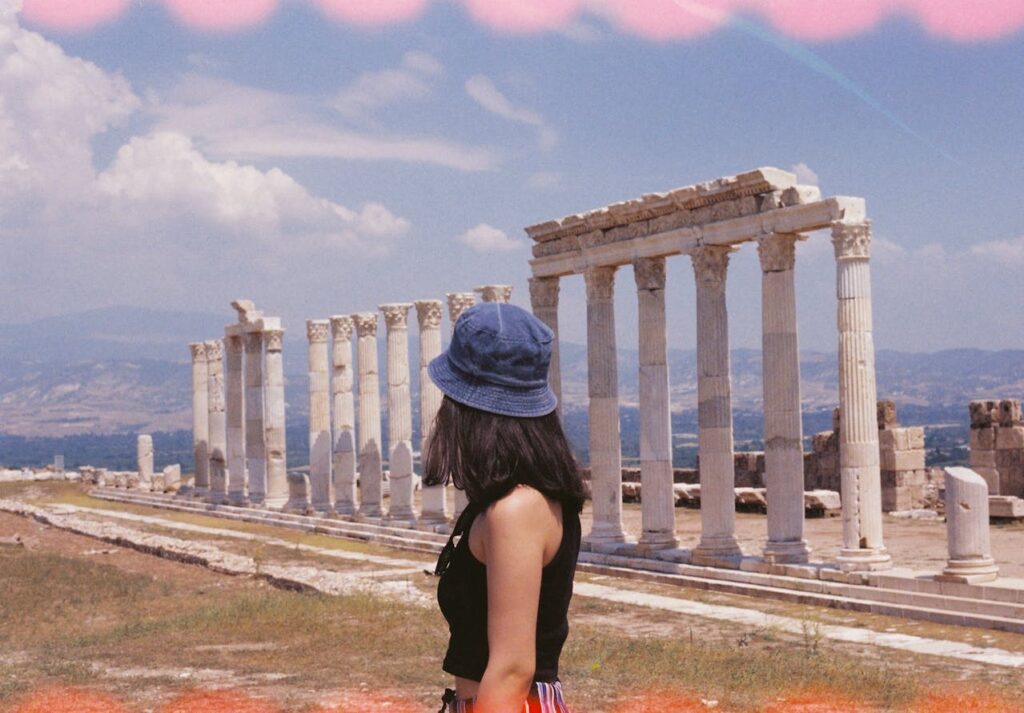 Eine junge Frau vor dem Parthenon in Athen bei Sonnenuntergang.