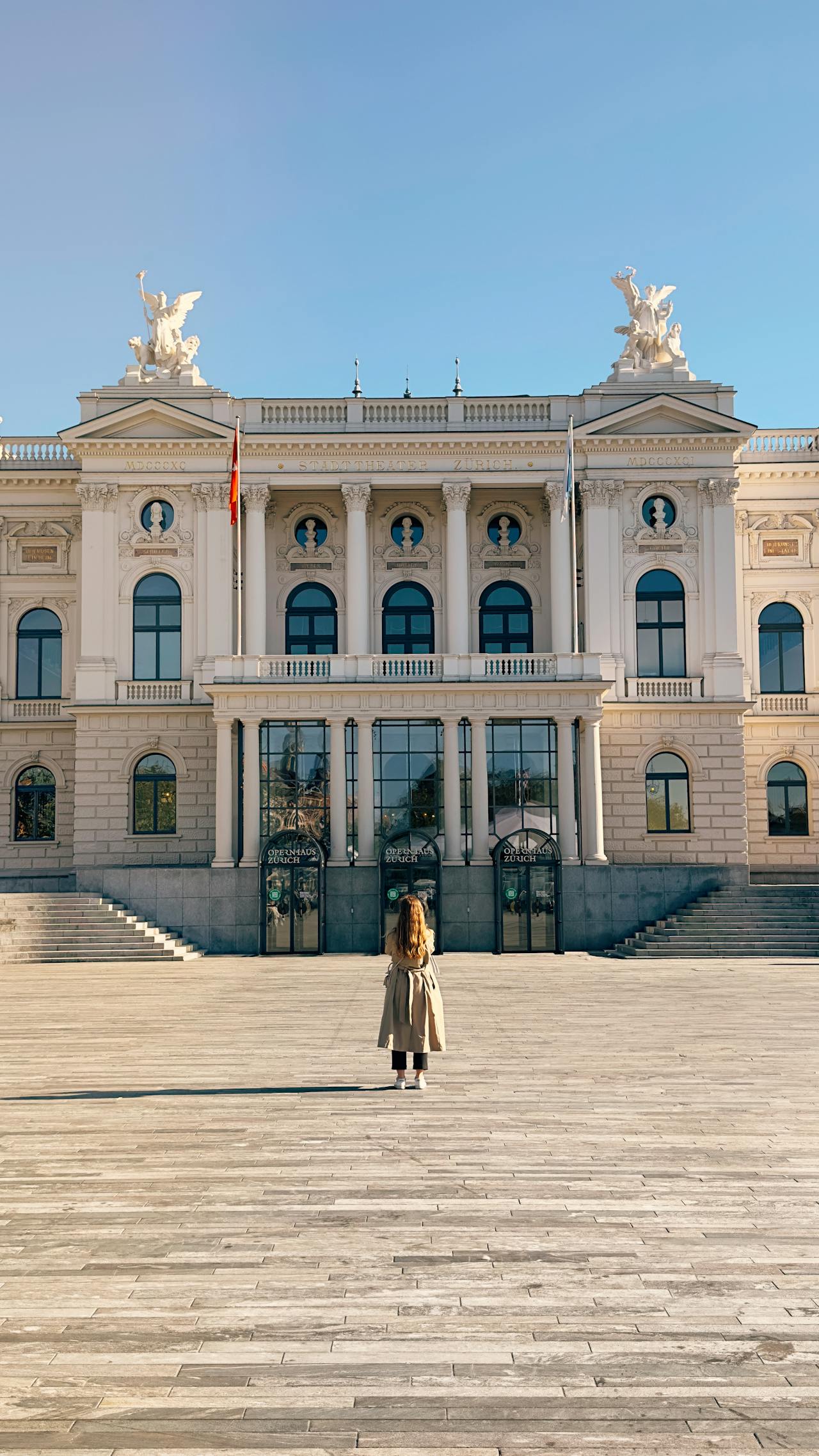 eine Frau im Mantel vor dem Opernhaus Zürich in der Schweiz stehend