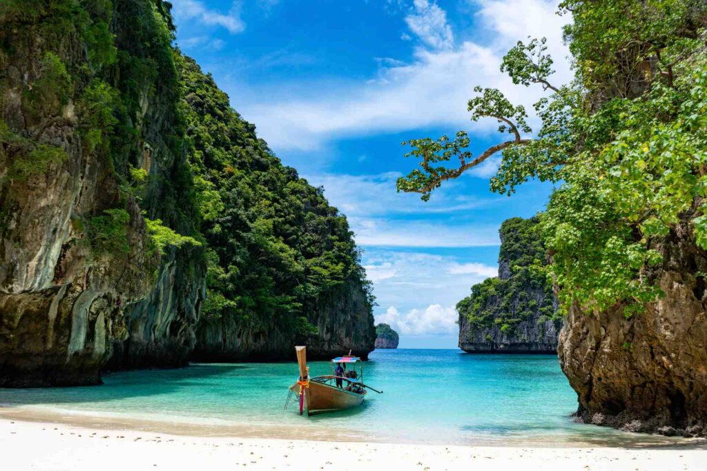 Ein Blick auf den Strand von Maya in Thailand mit seinem klaren Wasser und einem Holzboot in der Nähe des Strandes.