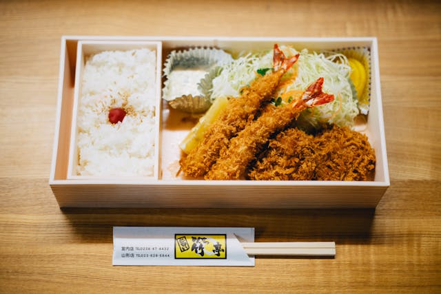 Ein Bento bestehend aus Ebi Tempura Bento auf einem braunen Holztisch