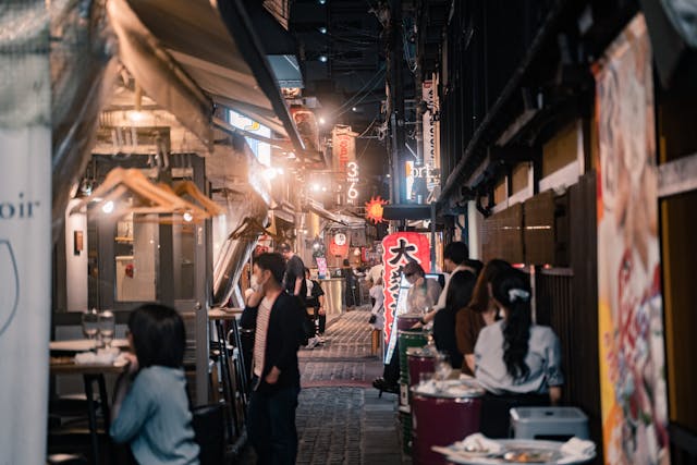 Menschen in einer Gasse mit street food Ständen in Osaka, Osaka, Japan