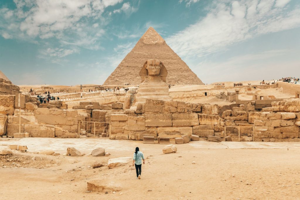 Un homme vu de dos marchant en direction de la pyramide de Gizeh en Egypte.