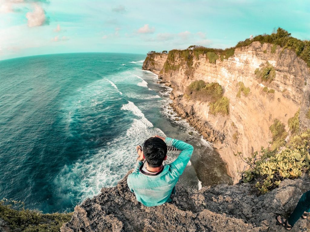 Une personne prenant une photo de la mer depuis une falaise à Bali, Indonésie.