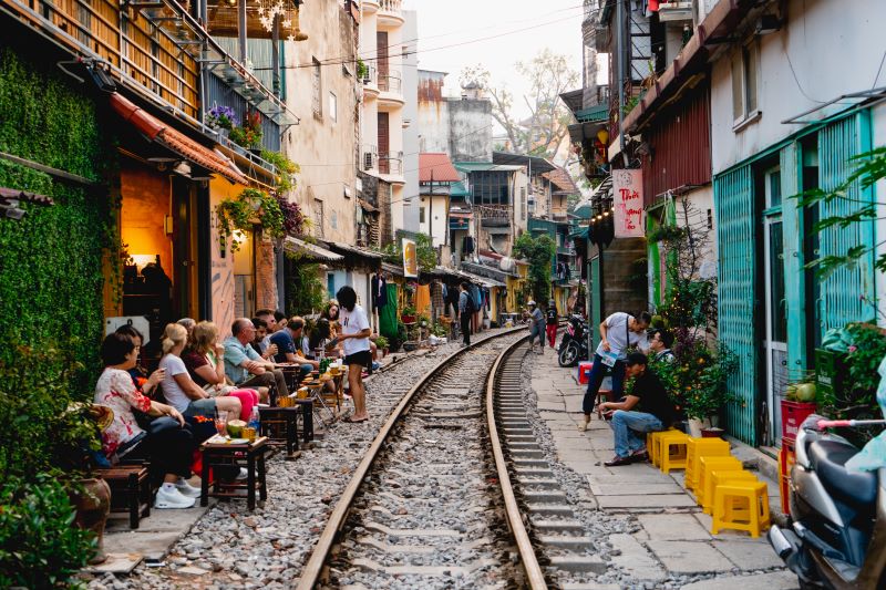 Des personnes attablées en terrasse dans une petite rue au Vietnam.