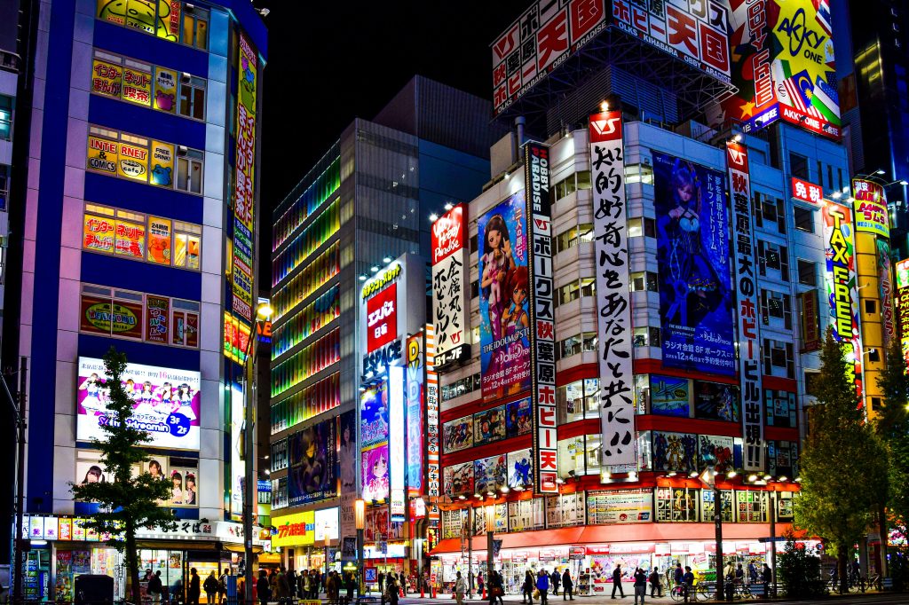 Photo de nuit du quartier Akihabara à Tokyo avec les neons et affiches manga