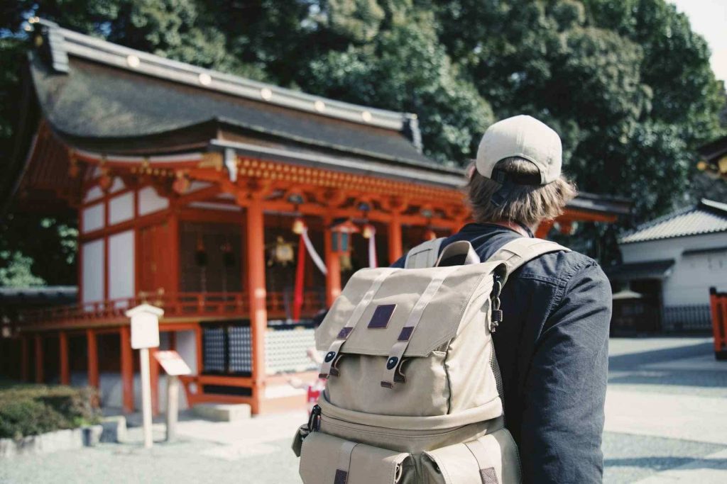Uomo turista che passa davanti a un tempio rosso in Giappone