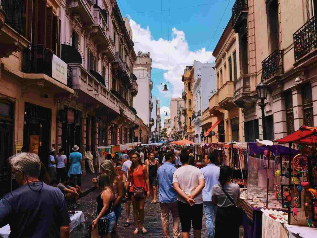 Turisti che passeggiano in un quartiere popolare di Buenos Aires acquistando oggetti di artigianato.