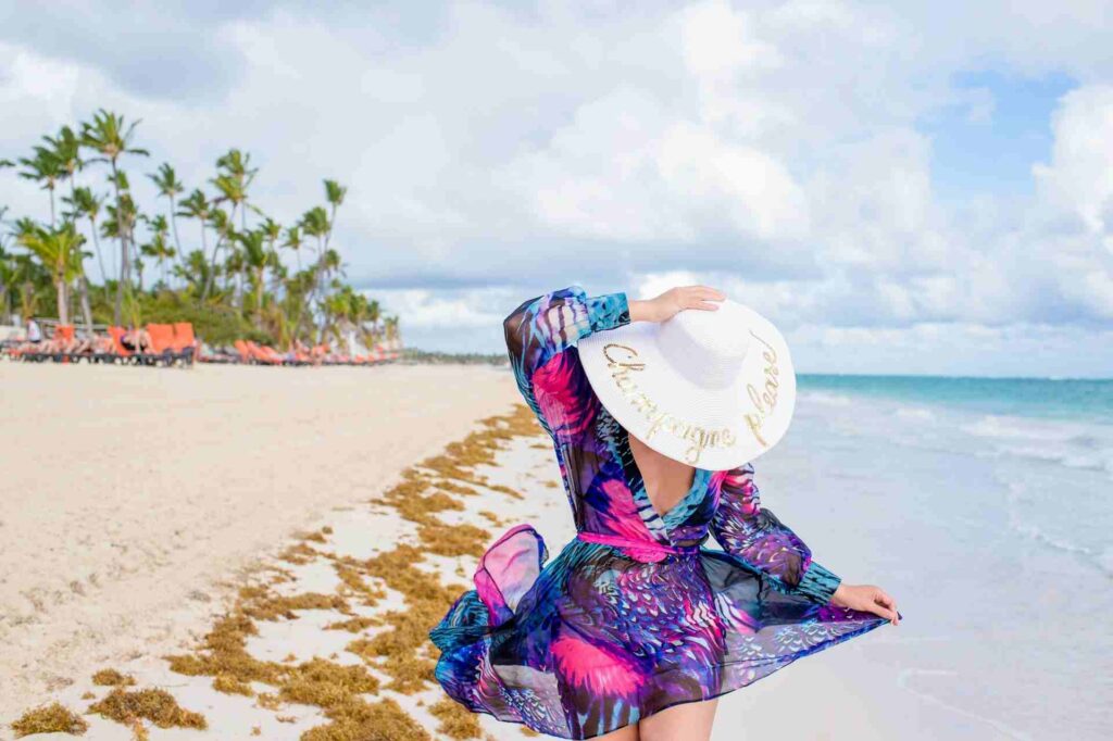 Donna in tenuta da spiaggia e cappello che cammina in riva al mare a Punta Cana