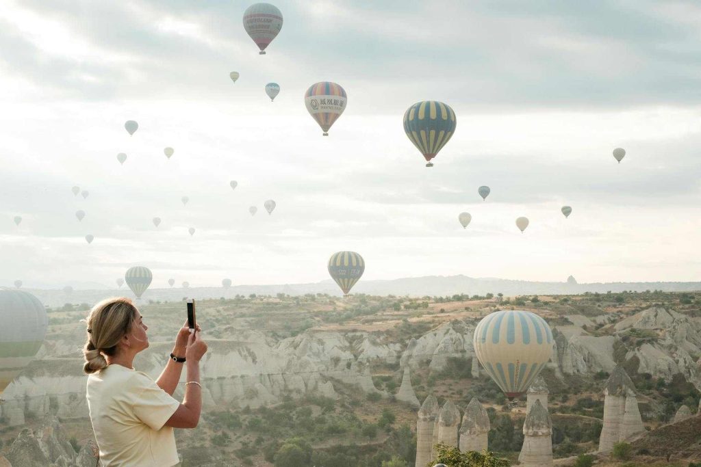 Donna che scatta una foto ai palloni aerostatici in un punto panoramico in cappadocia