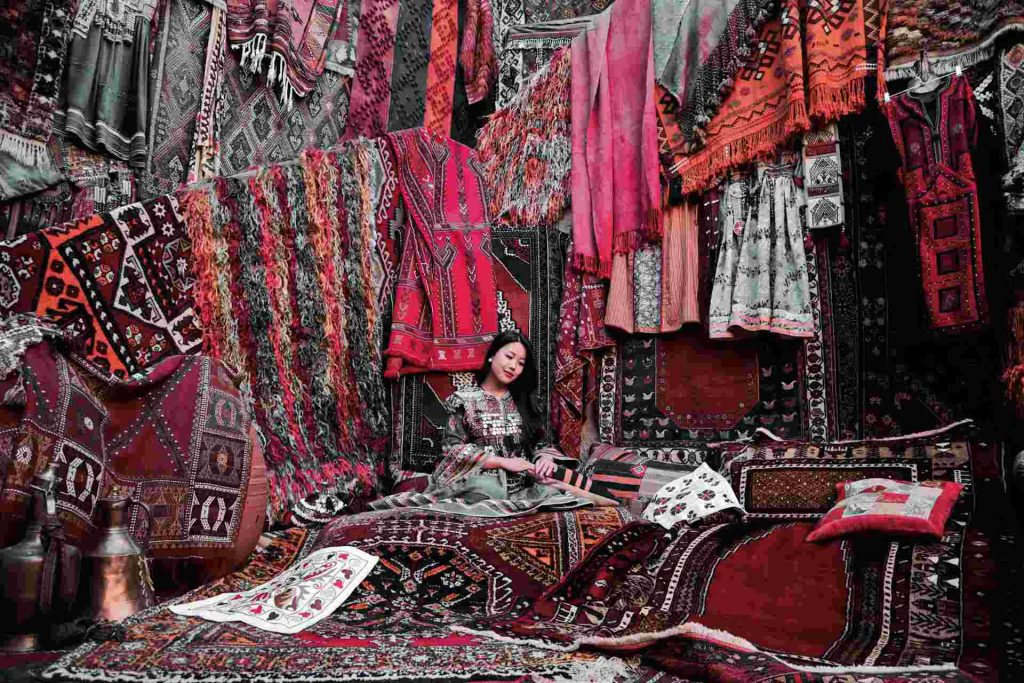 Donna in abiti tipici seduta al centro di un bazar in Cappadocia.