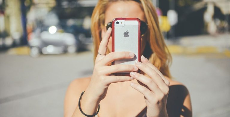 Donna che usa il suo cellulare iPhone all'aperto.