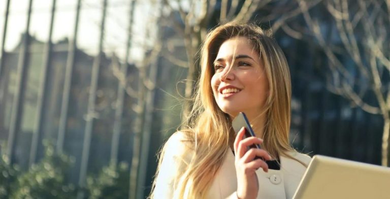 Donna che usa il telefono e il computer portatile all'aperto