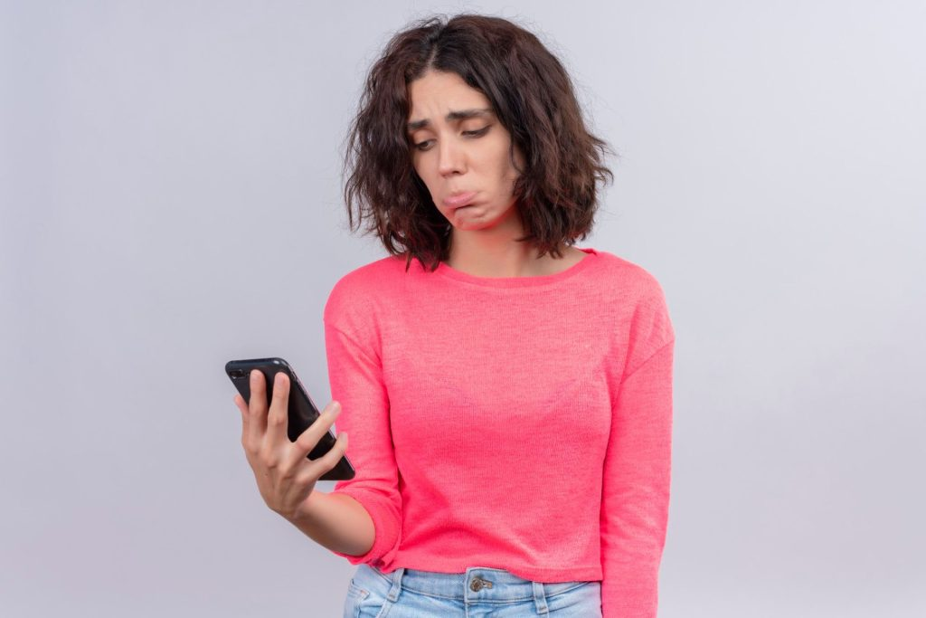 Donna che guarda il suo telefono con espressione triste