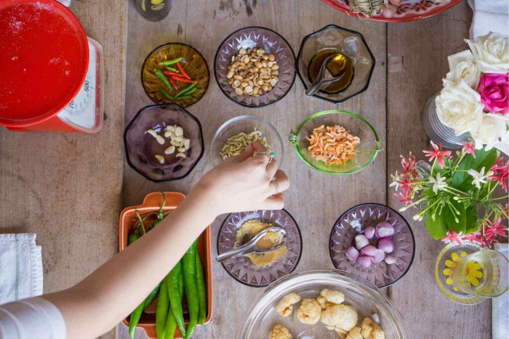 Persona che dispone gli ingredienti tipici thailandesi su un tavolo.