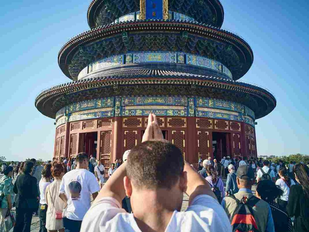 Turistas e praticantes do budismo saudando um tempo budista em Pequim, China.