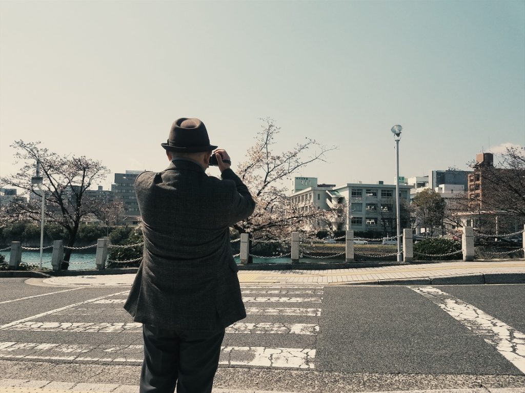 Local taking a picture of the cherry blossoms on a street in Japan