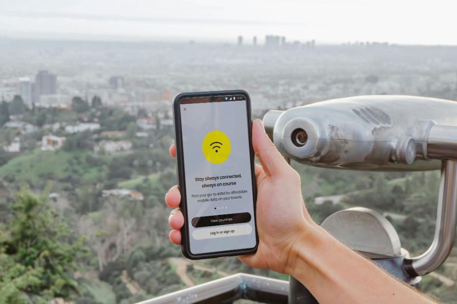 A hand holding a smartphone connecting to eSIM