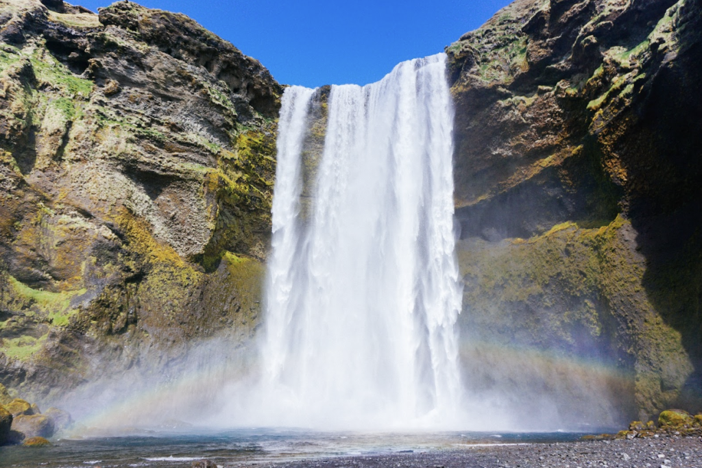 Mountain and waterfall in Iceland, with a faint rainbow in front