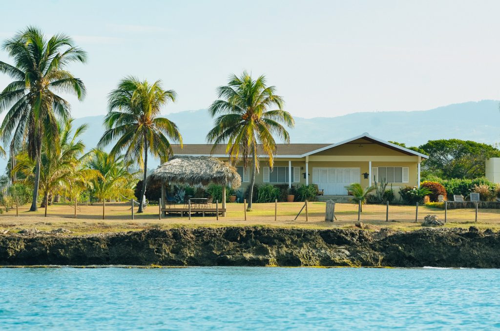 A house on the water surrounded by palm trees in Jamaica.
